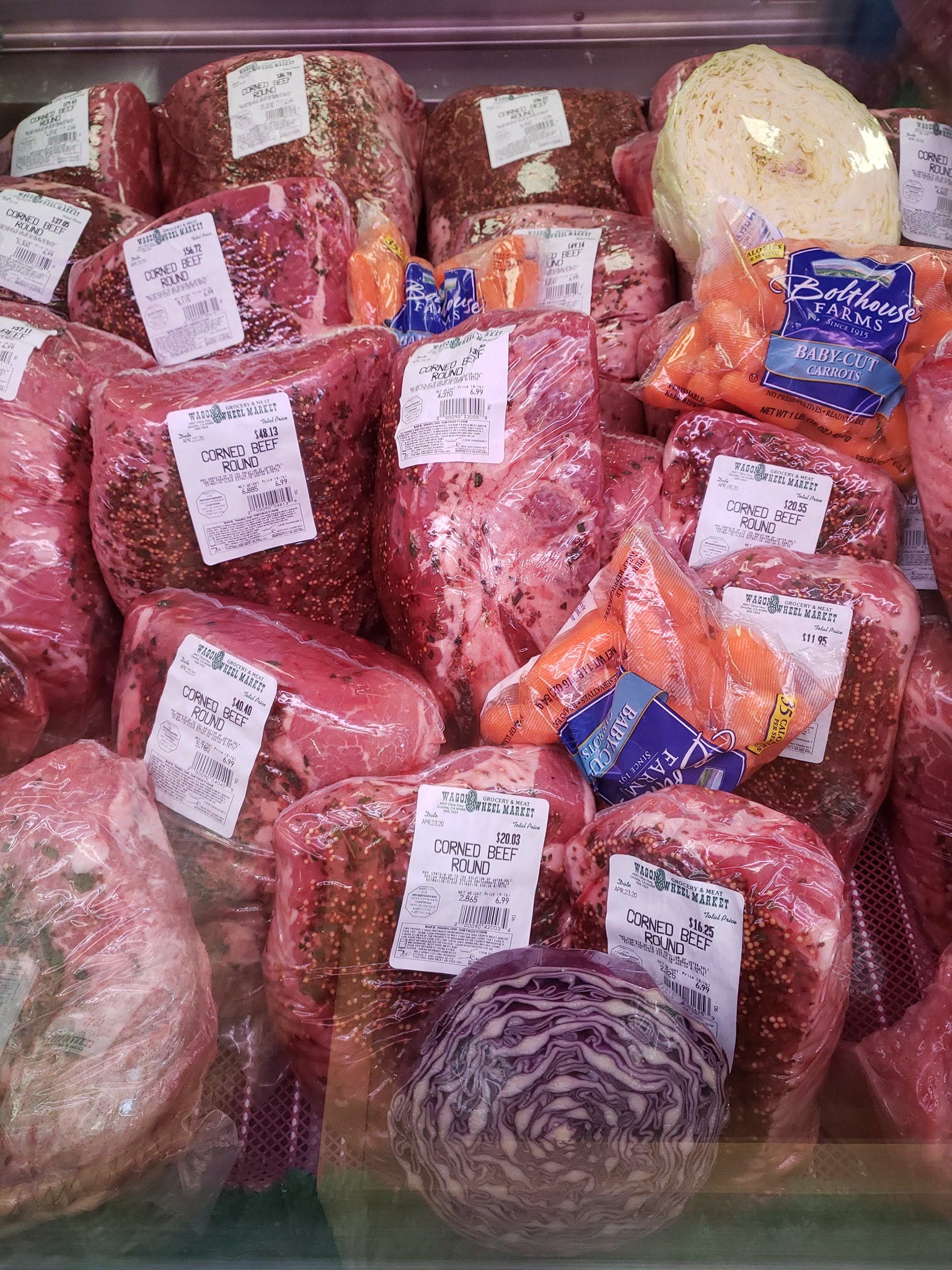 The meat case stacked with house-labelled corned beef rounds, cabbage and carrots