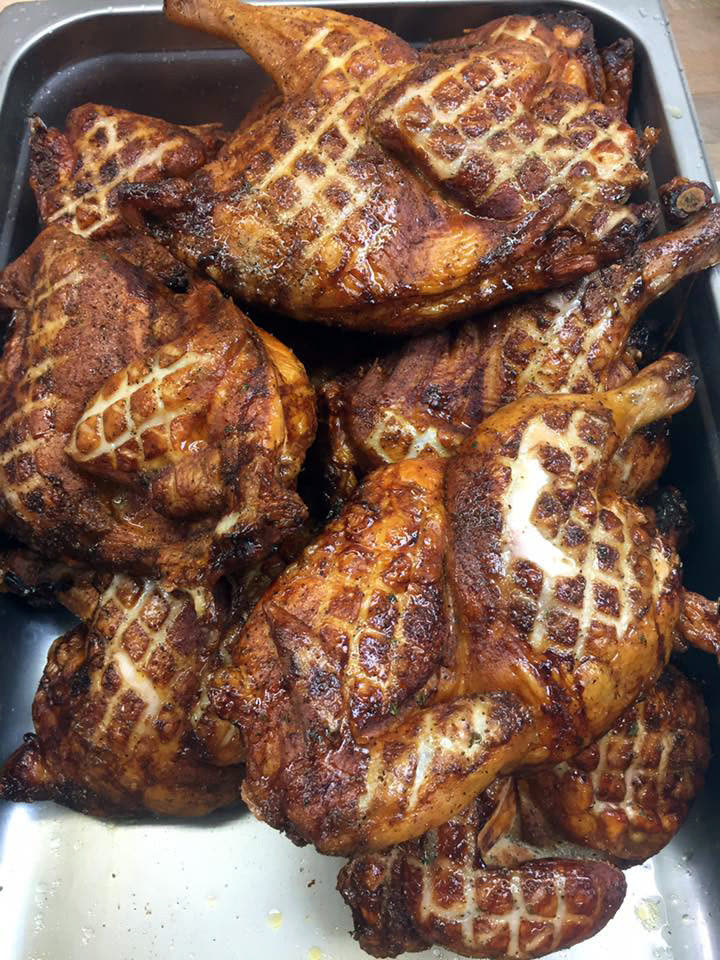 A tray of scored, golden rotisserie chickens straight from the oven